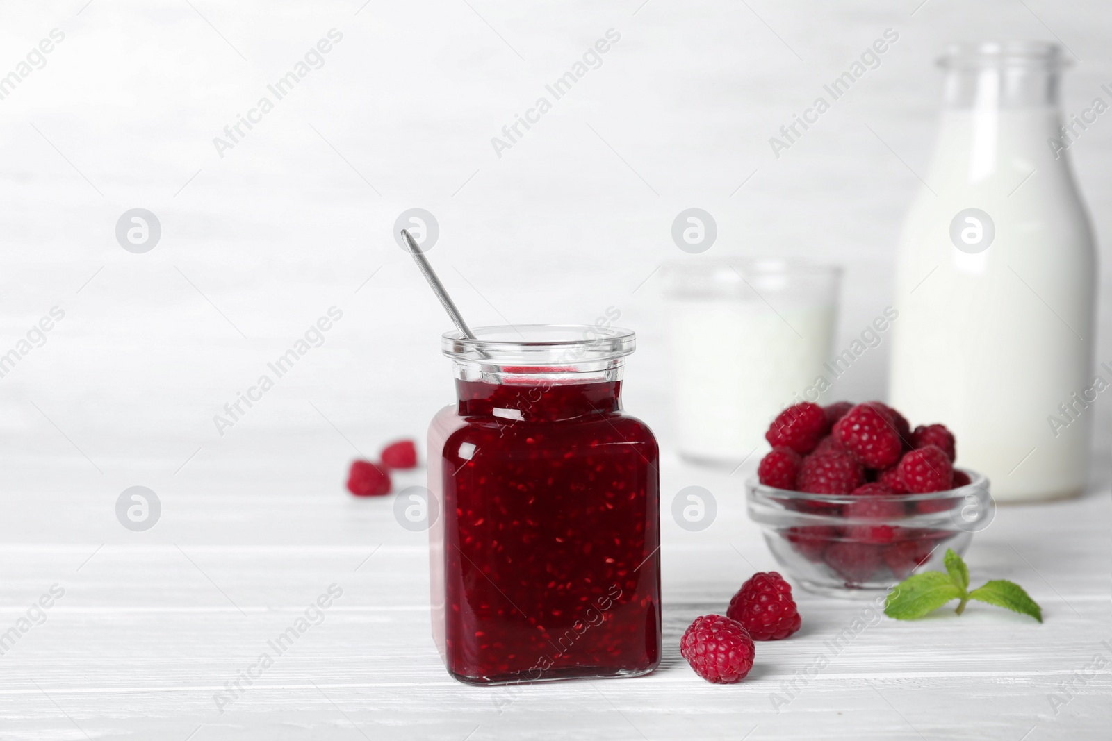 Photo of Jar with delicious raspberry jam on table