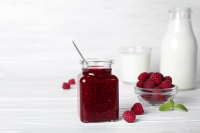 Photo of Jar with delicious raspberry jam on table