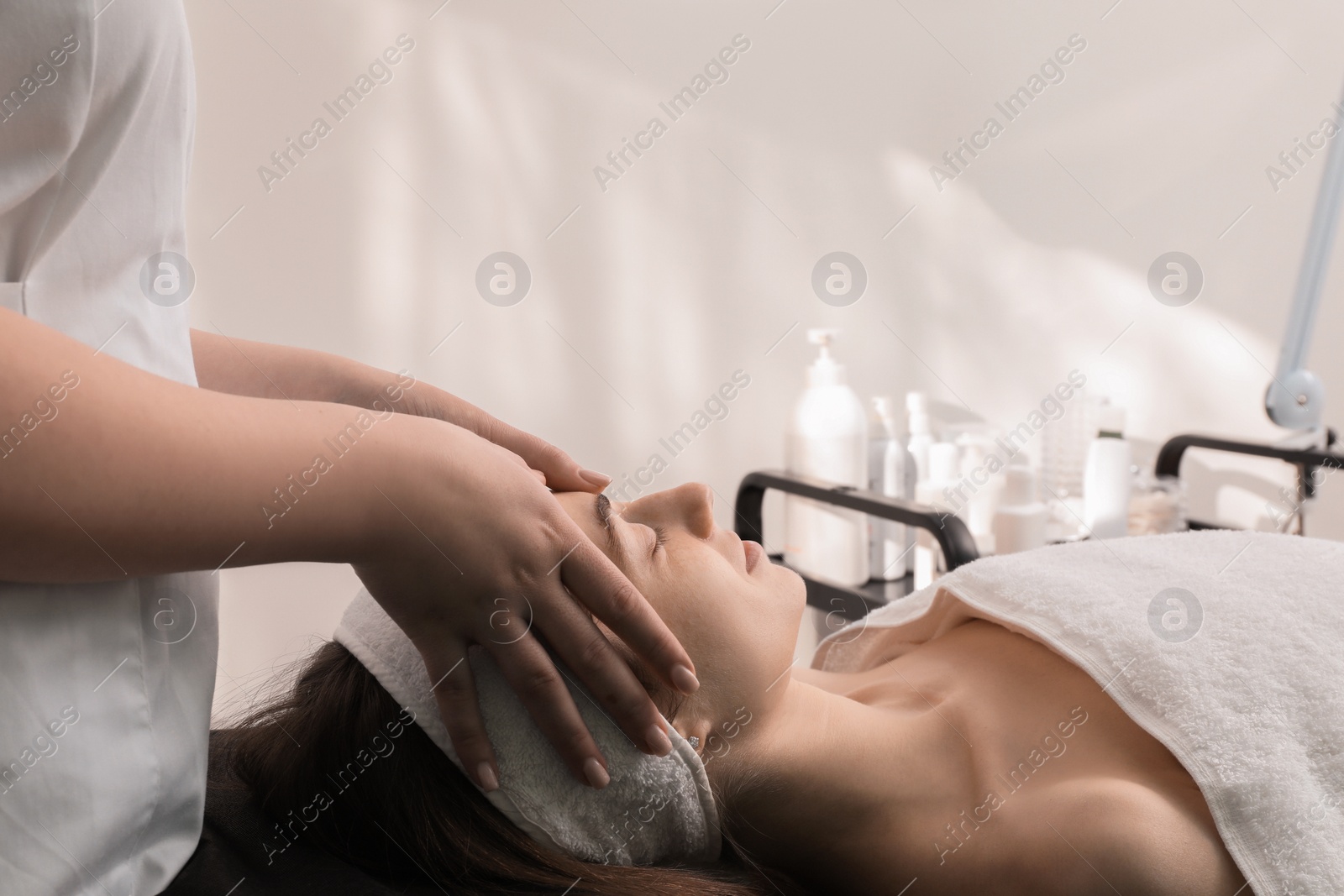 Photo of Cosmetologist making face massage to client in clinic, closeup