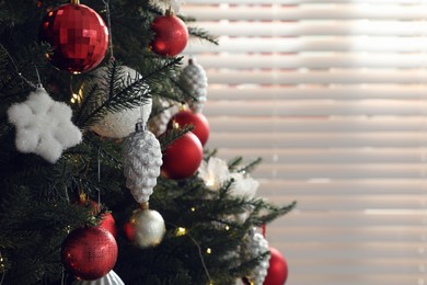 Photo of Beautifully decorated Christmas tree near window indoors, closeup. Space for text