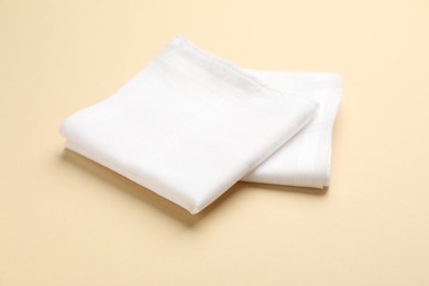 Photo of White handkerchiefs on beige background. Stylish accessory