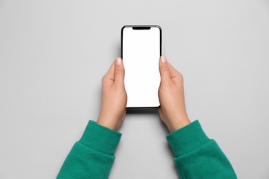 Photo of Woman with smartphone on light grey background, top view