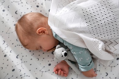 Photo of Adorable baby with toy sleeping in crib, top view