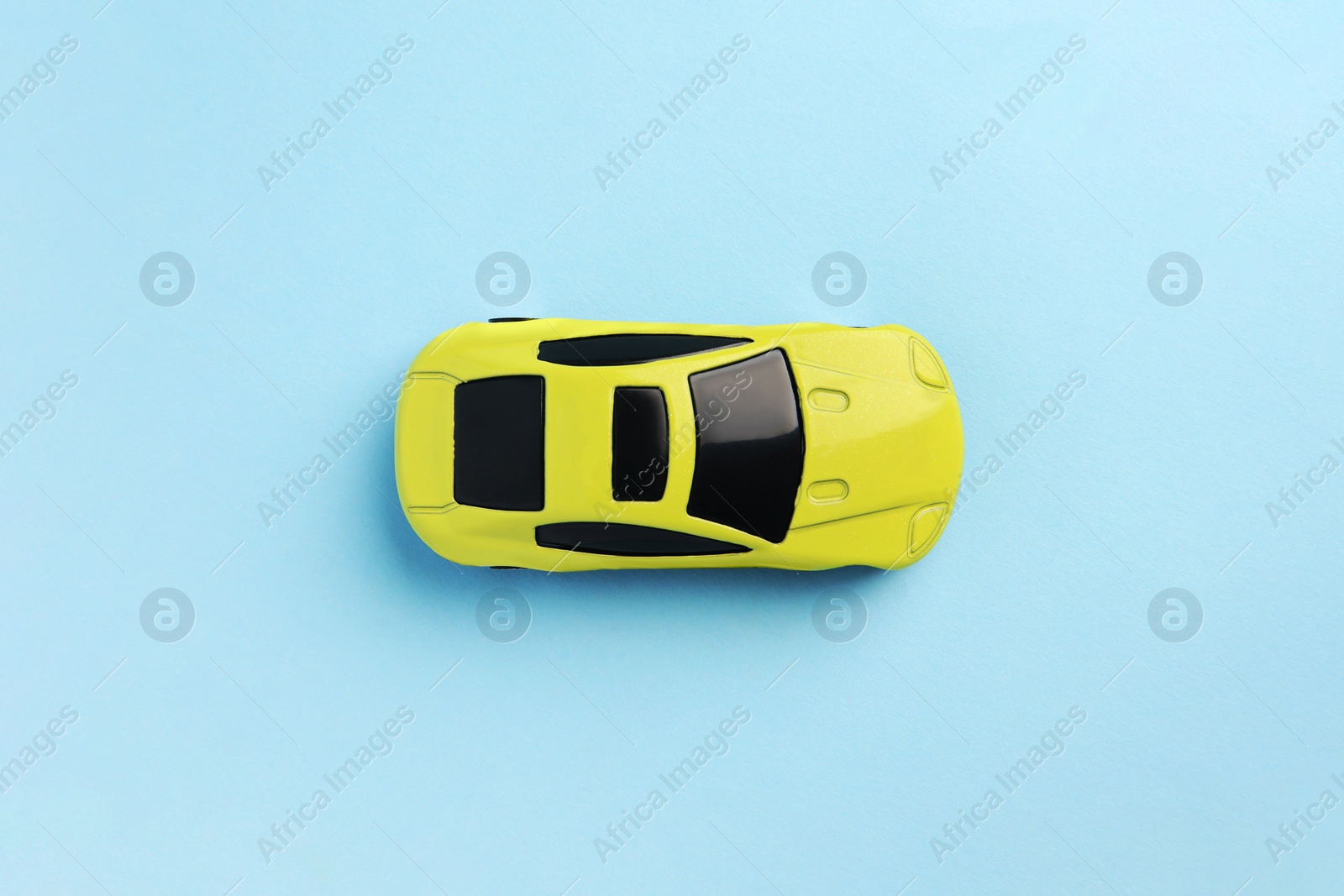 Photo of One yellow car on light blue background, top view. Children`s toy