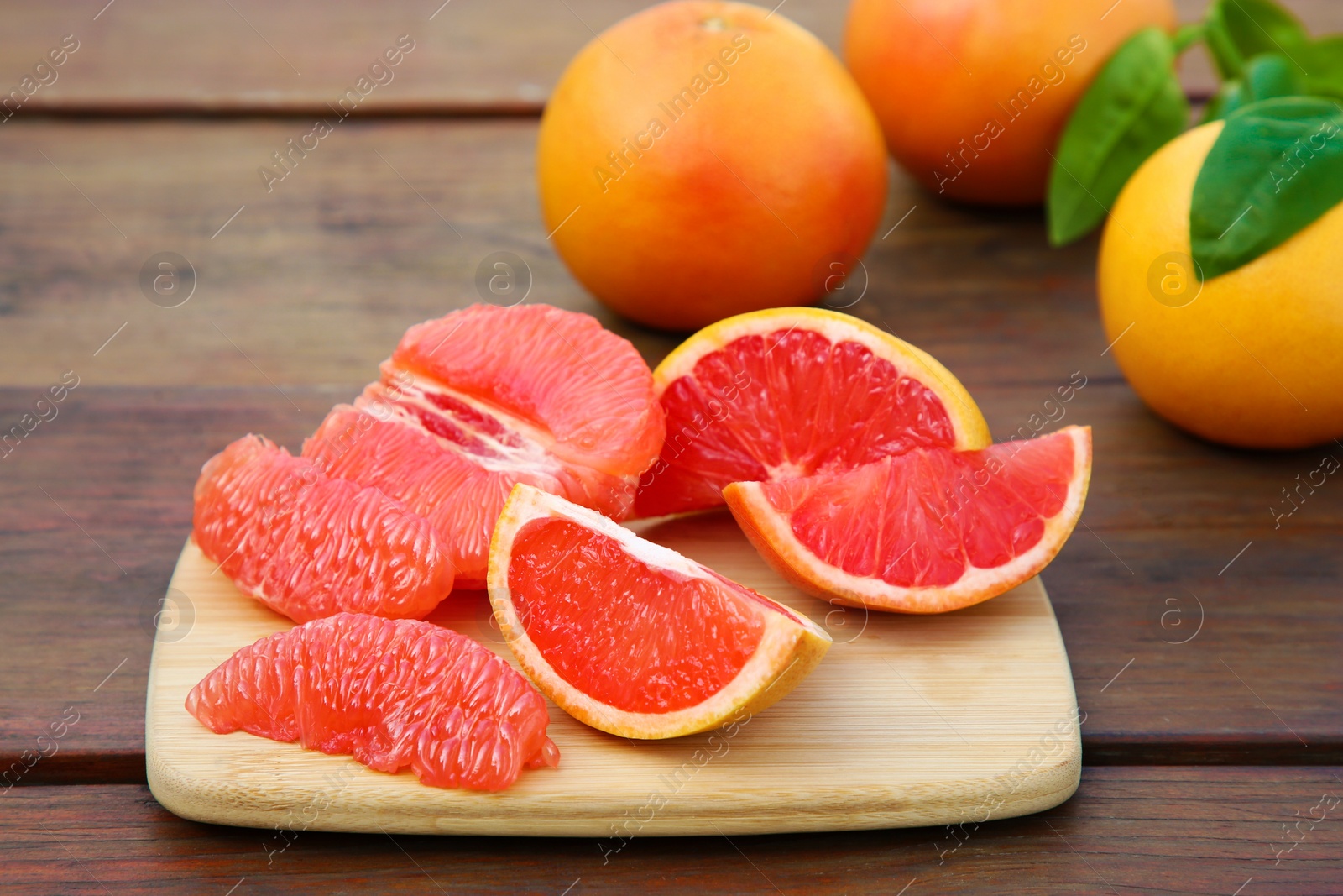 Photo of Cut and whole fresh ripe grapefruits on wooden table
