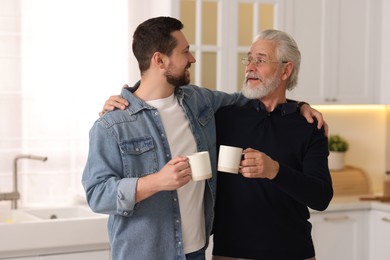 Photo of Happy son and his dad with cups at home