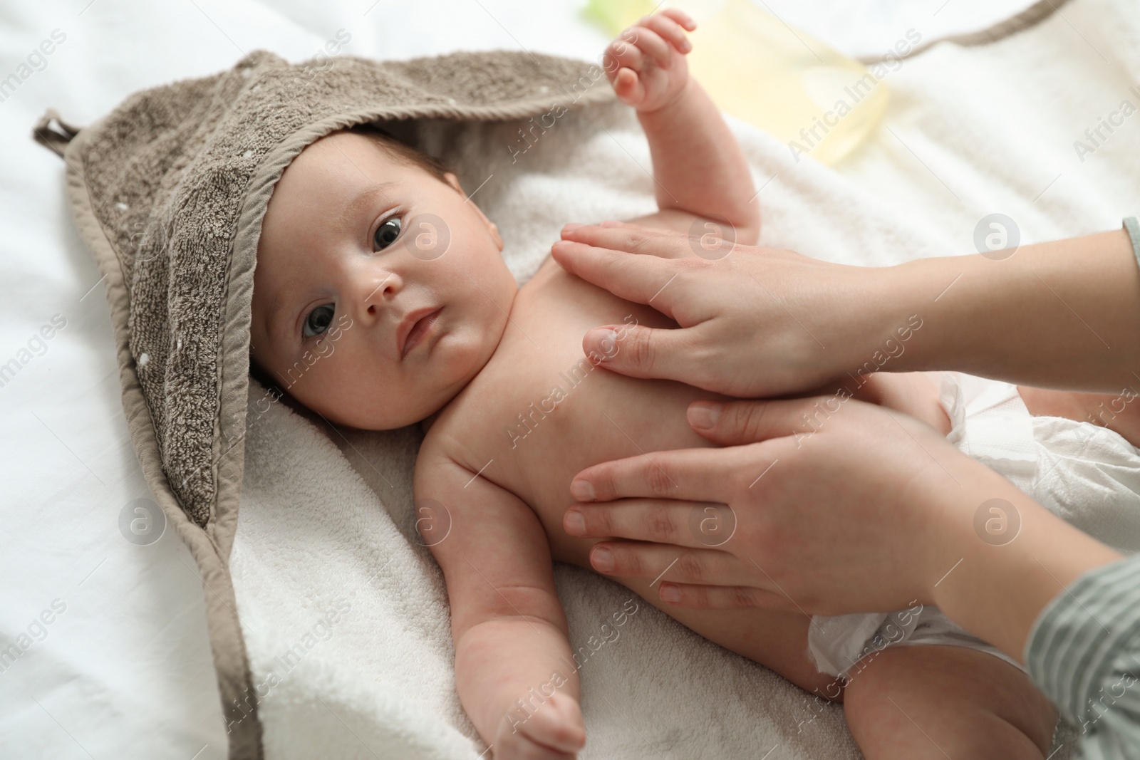 Photo of Mother massaging her cute baby with oil, closeup