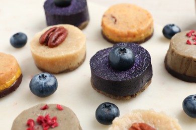 Photo of Different delicious vegan candies on white table, closeup