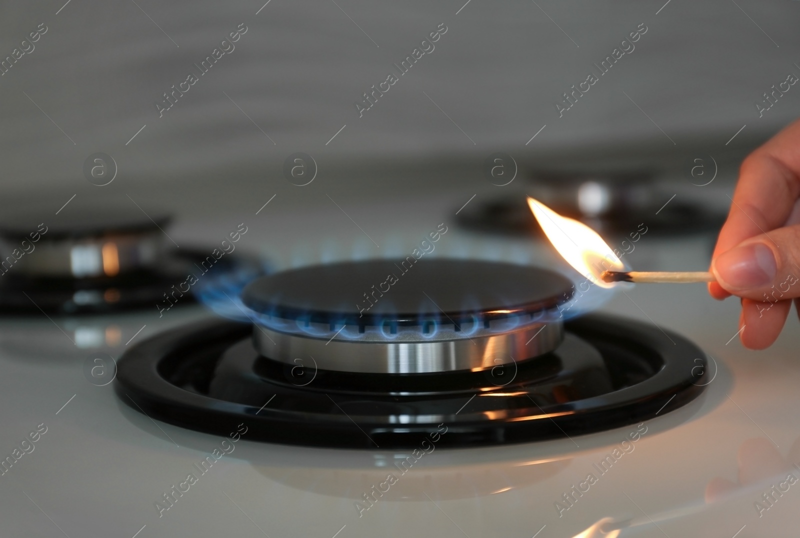 Photo of Woman lighting gas stove with match, closeup