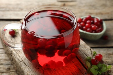 Photo of Delicious cranberry tea and berries on wooden table, closeup