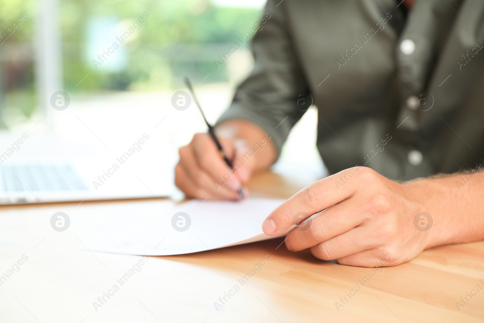 Photo of Male notary signing document at table in office, closeup