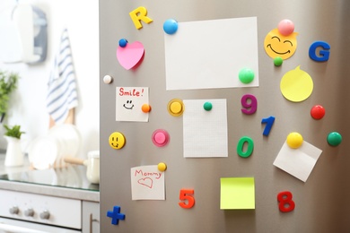 Many notes and empty sheets with magnets on refrigerator door in kitchen. Space for text