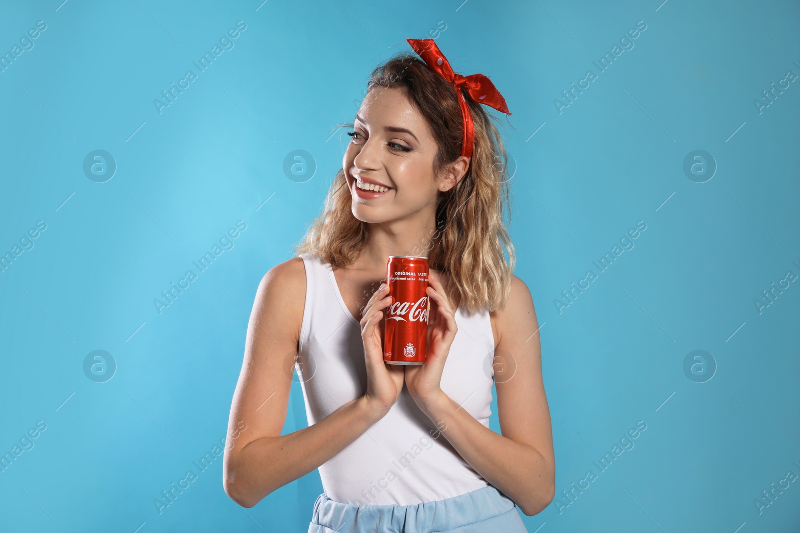 Photo of MYKOLAIV, UKRAINE - NOVEMBER 28, 2018: Young woman with Coca-Cola can on color background