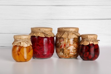 Photo of Many jars with different preserved products on light grey table