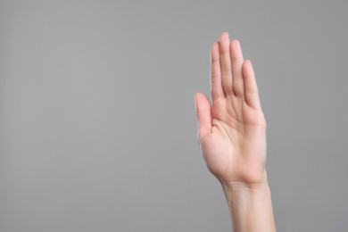 Photo of Woman giving high five on grey background, closeup. Space for text