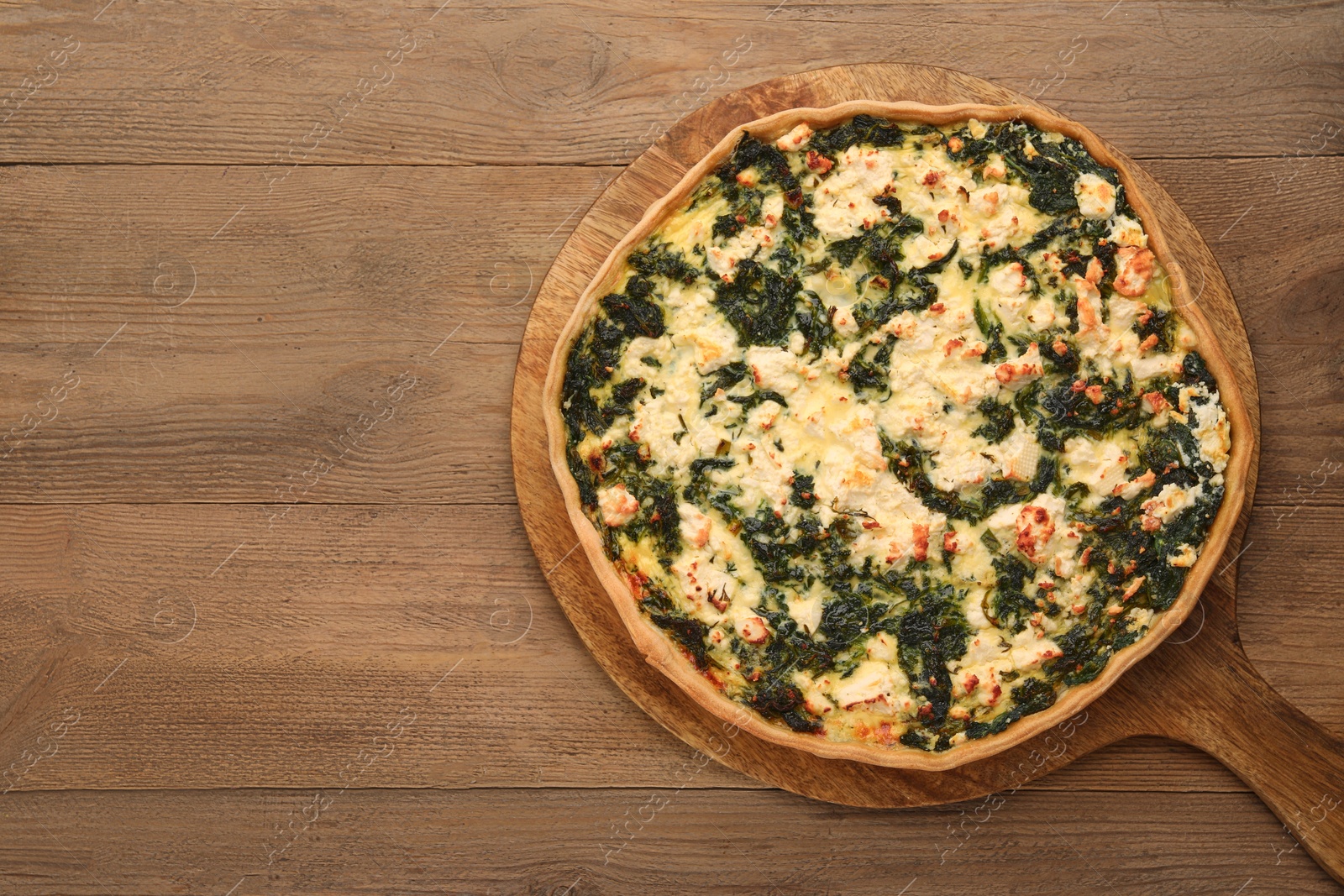 Photo of Delicious homemade spinach quiche on wooden table, top view. Space for text