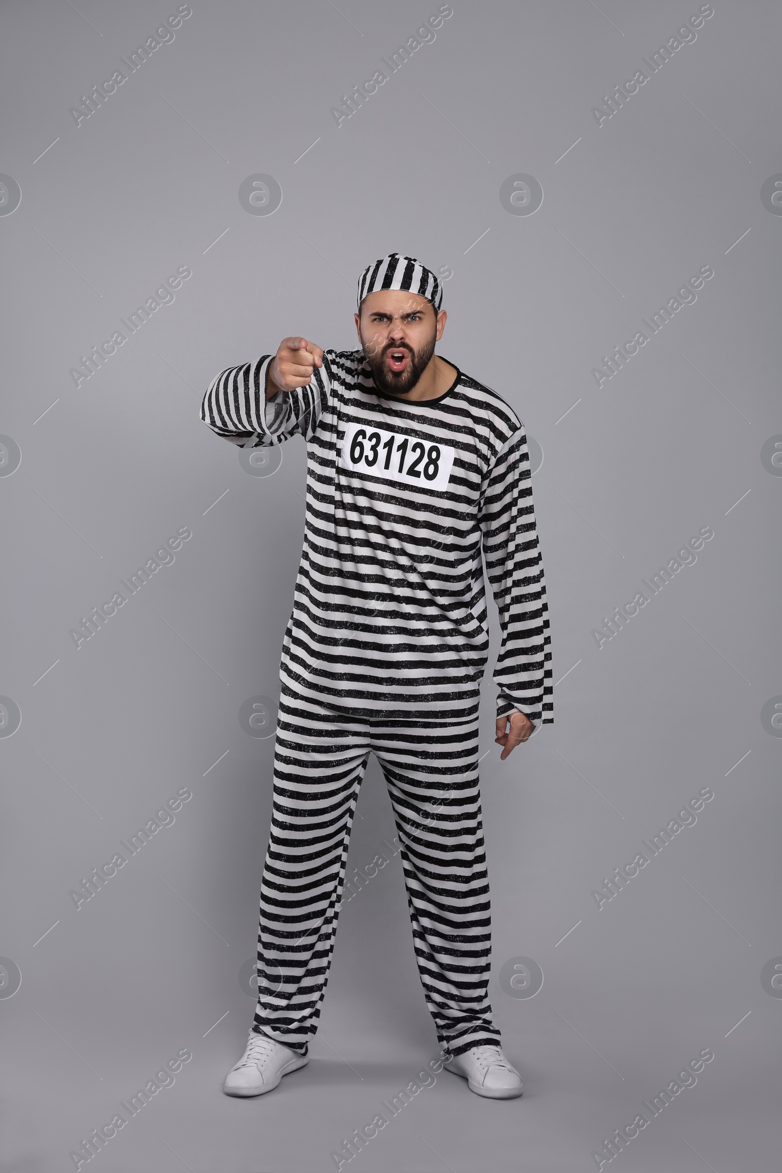 Photo of Emotional prisoner in special uniform on grey background