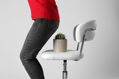 Photo of Woman sitting down on chair with cactus against white background, closeup. Hemorrhoids concept