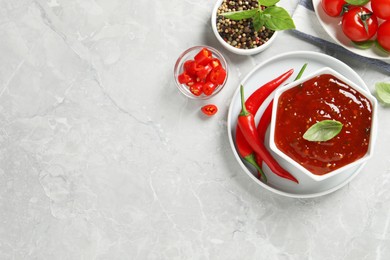 Photo of Spicy chili sauce and ingredients on light grey table, flat lay. Space for text