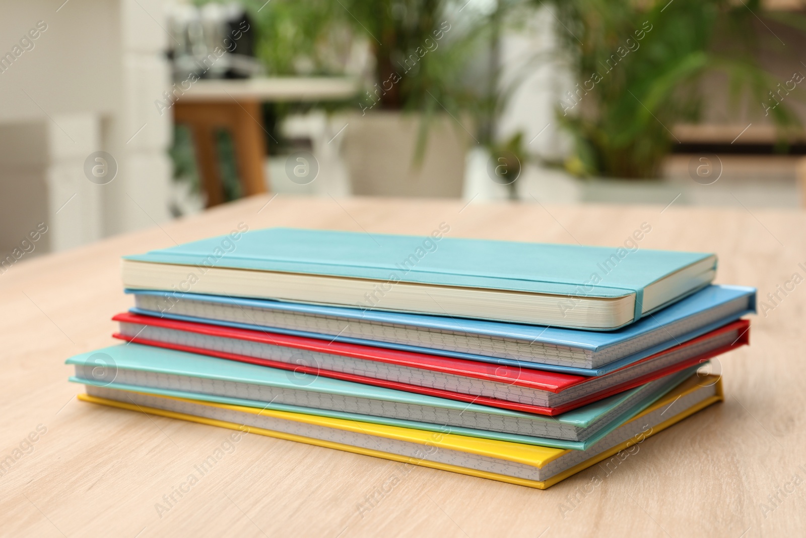 Photo of Stack of colorful planners on wooden table indoors