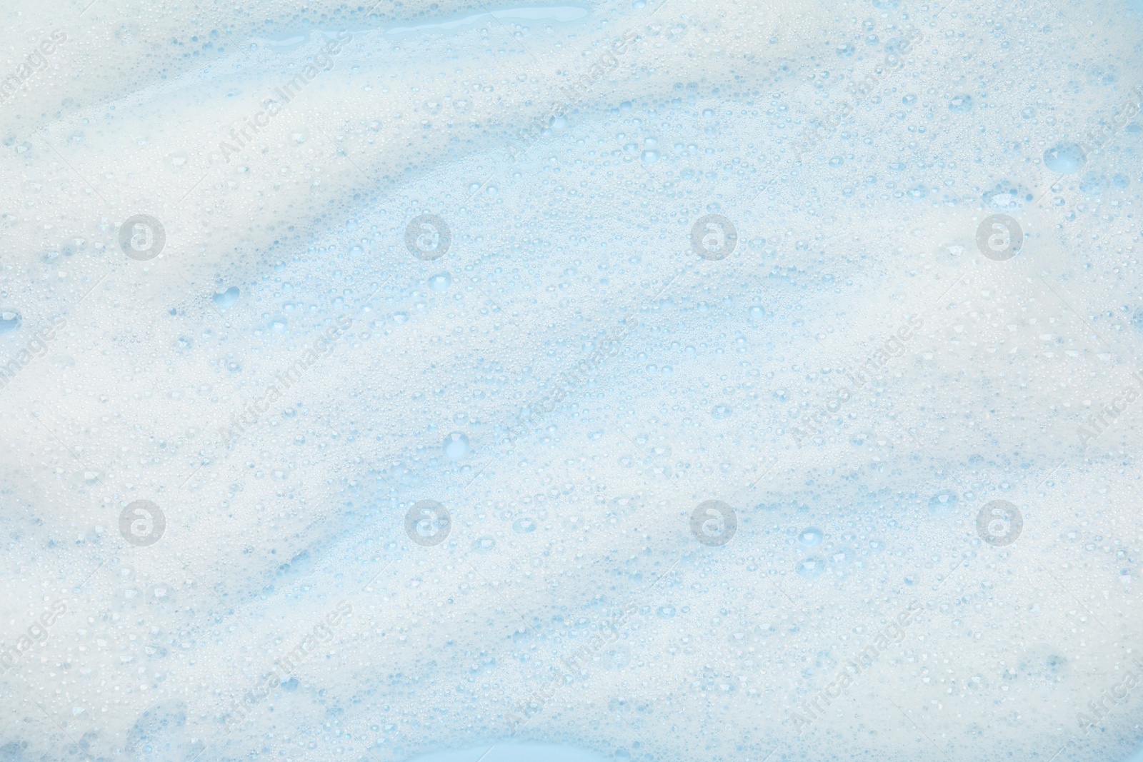 Photo of White washing foam on light blue background, top view