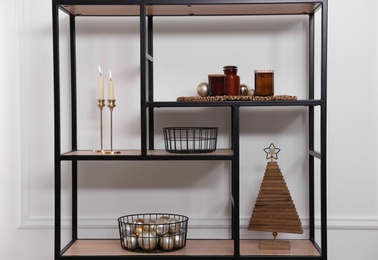 Photo of Stylish shelving unit with Christmas decor near white wall indoors. Interior design