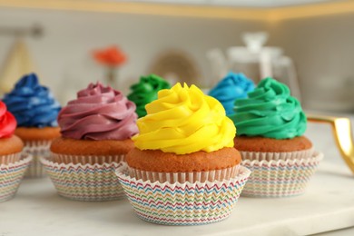 Photo of Delicious cupcakes with colorful cream on white board, closeup