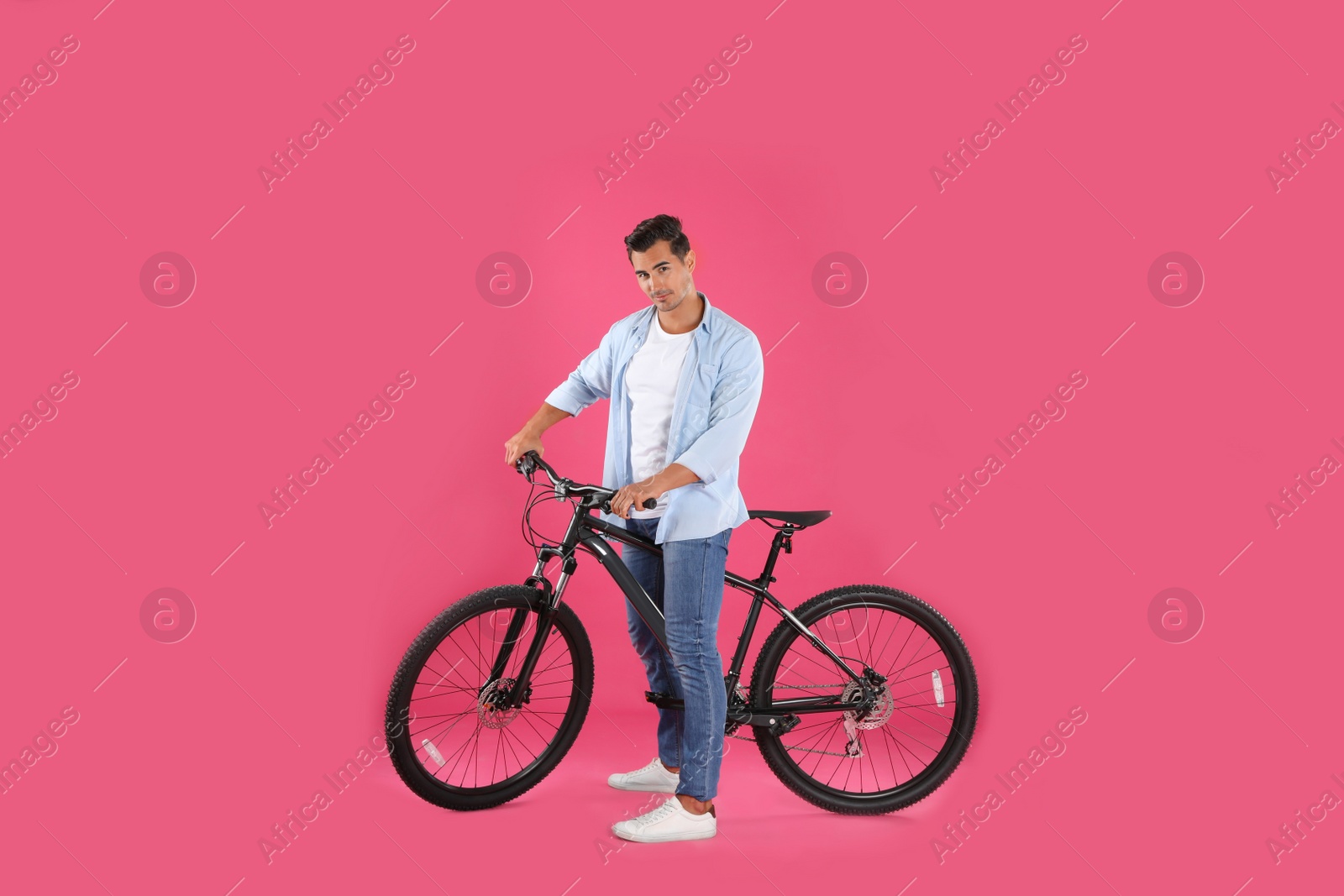 Photo of Handsome young man with modern bicycle on pink background