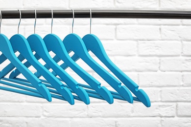 Photo of Clothes hangers on metal rail against brick wall background