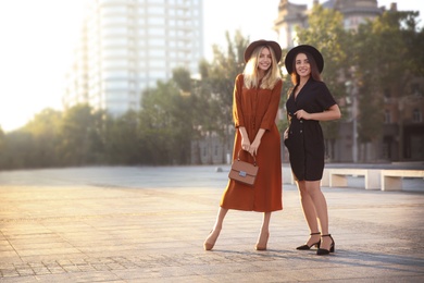 Photo of Beautiful young women in stylish dresses on city street