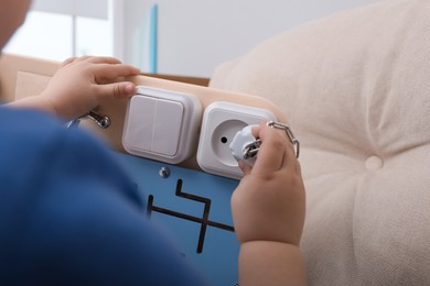 Little child playing with busy board on sofa, closeup