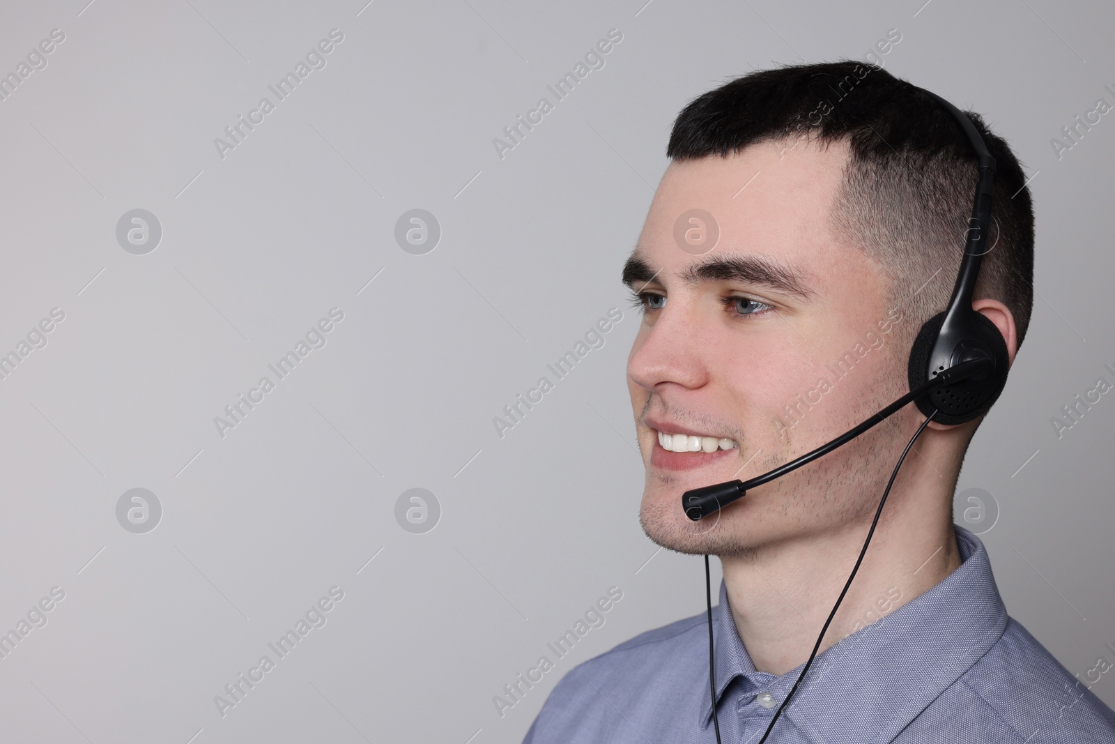 Photo of Hotline operator with headset on light grey background, space for text