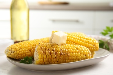 Fresh grilled corn cobs with butter on white wooden table, closeup