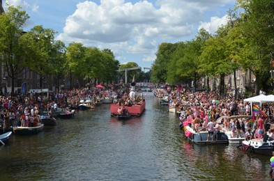 Photo of AMSTERDAM, NETHERLANDS - AUGUST 06, 2022: Many people in boats at LGBT pride parade on river