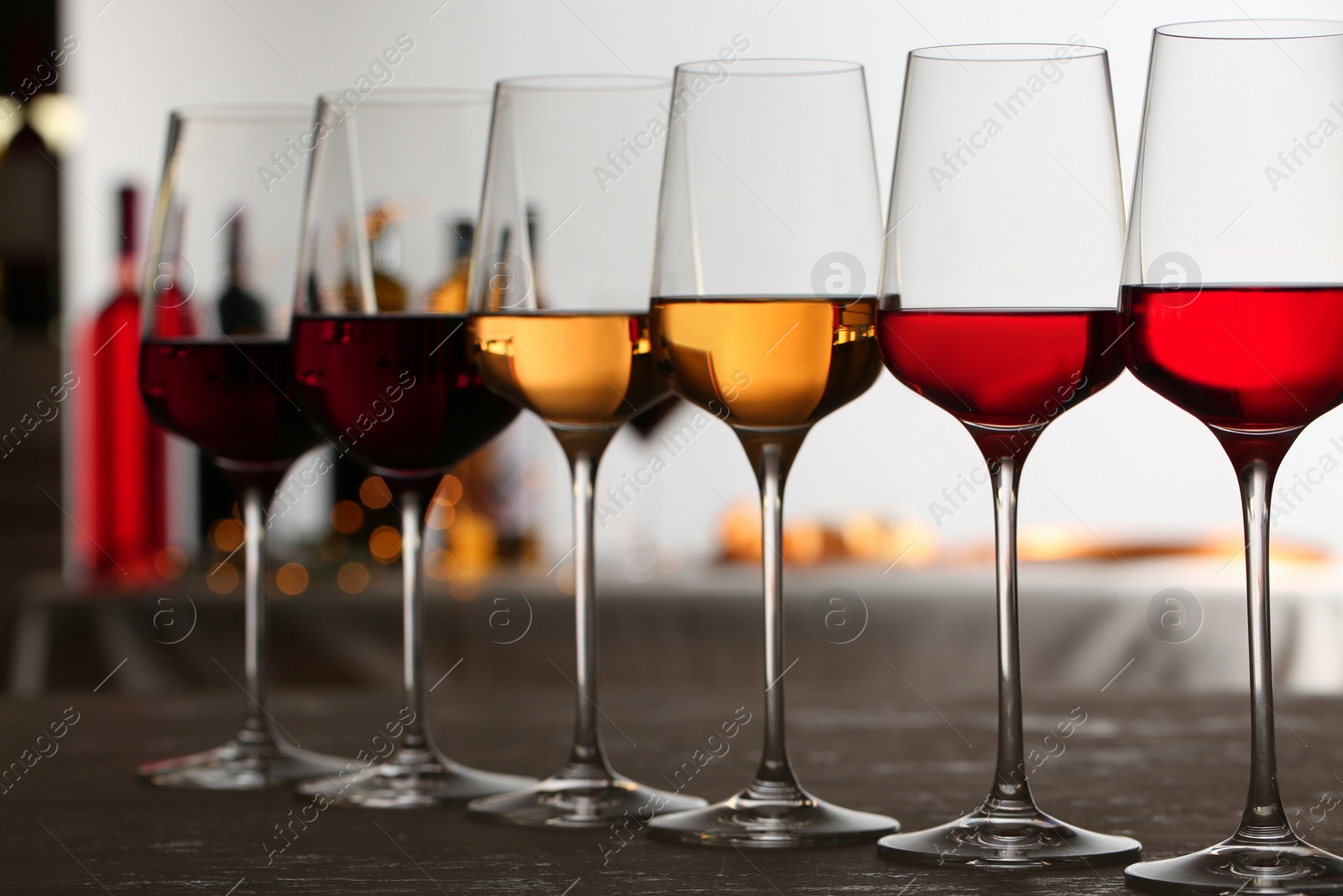 Photo of Row of glasses with different wines on table against blurred background