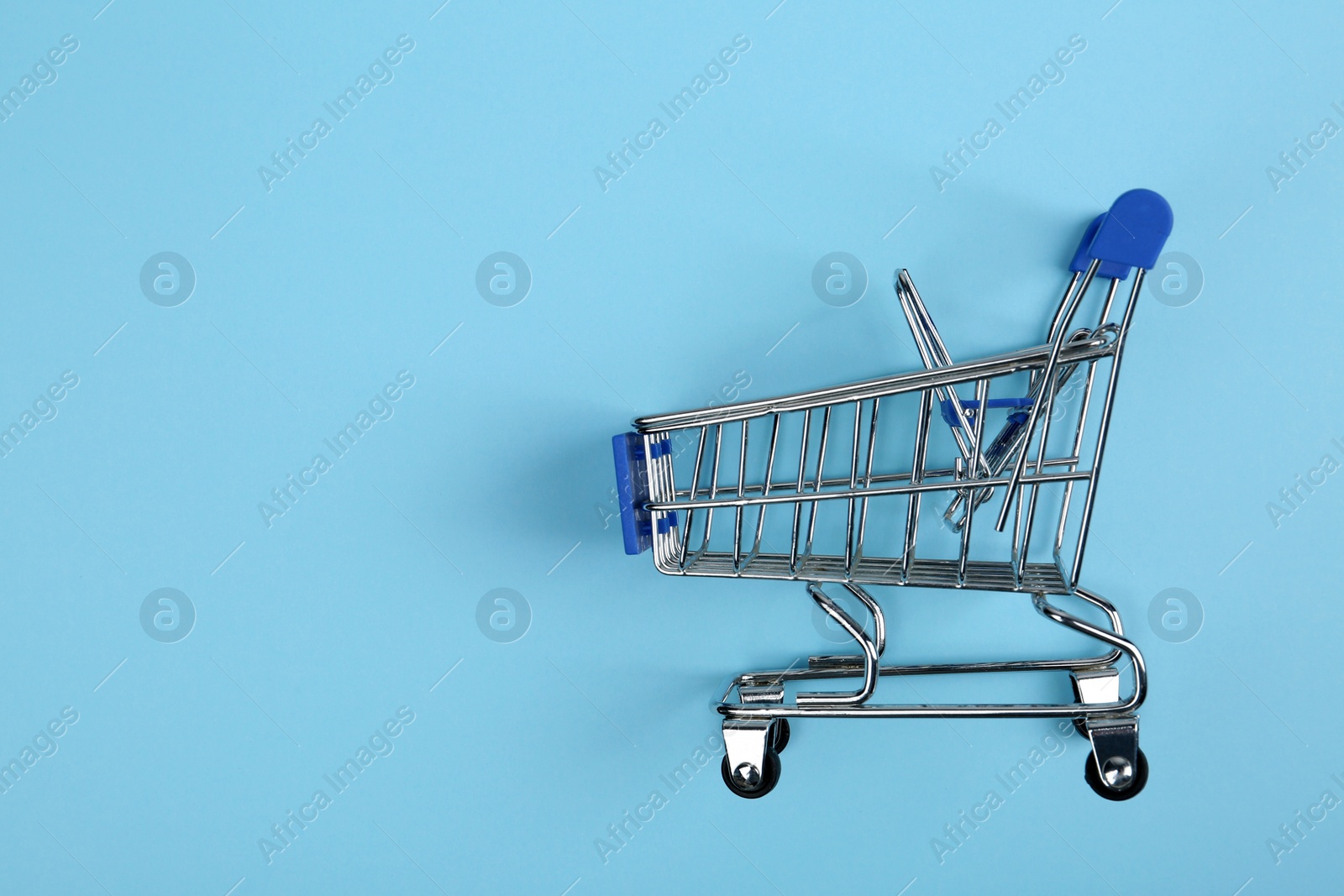 Photo of Empty shopping trolley on color background, top view. Space for text