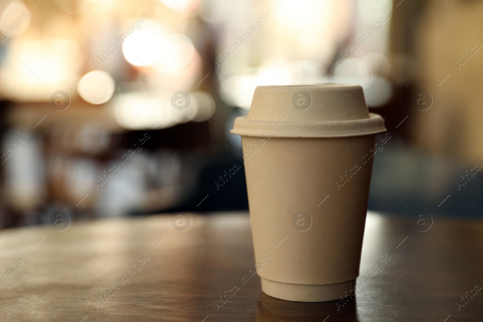 Photo of Cardboard takeaway coffee cup with lid on wooden table in outdoor cafe, space for text