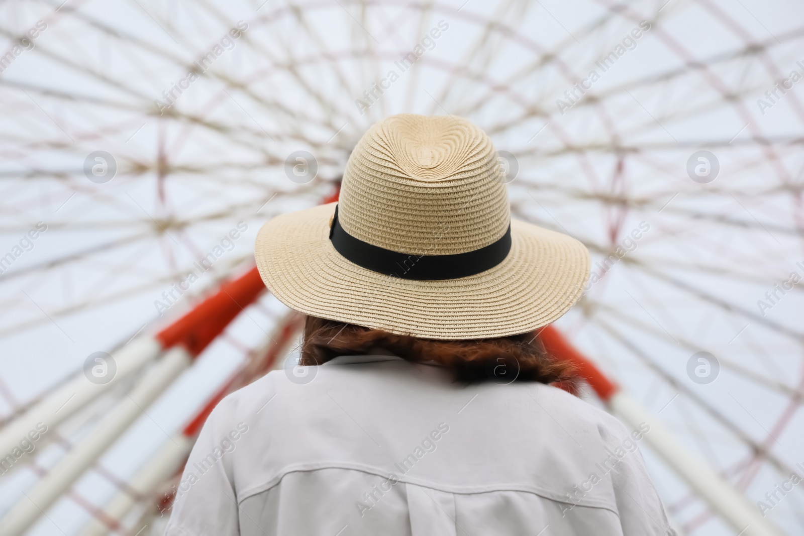 Photo of Young woman near Ferris wheel outdoors, back view