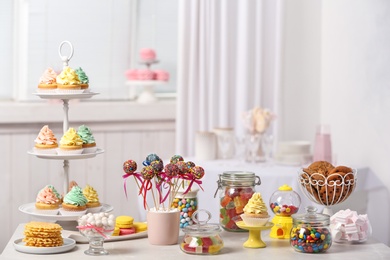 Candy bar with different sweets on white table against blurred background