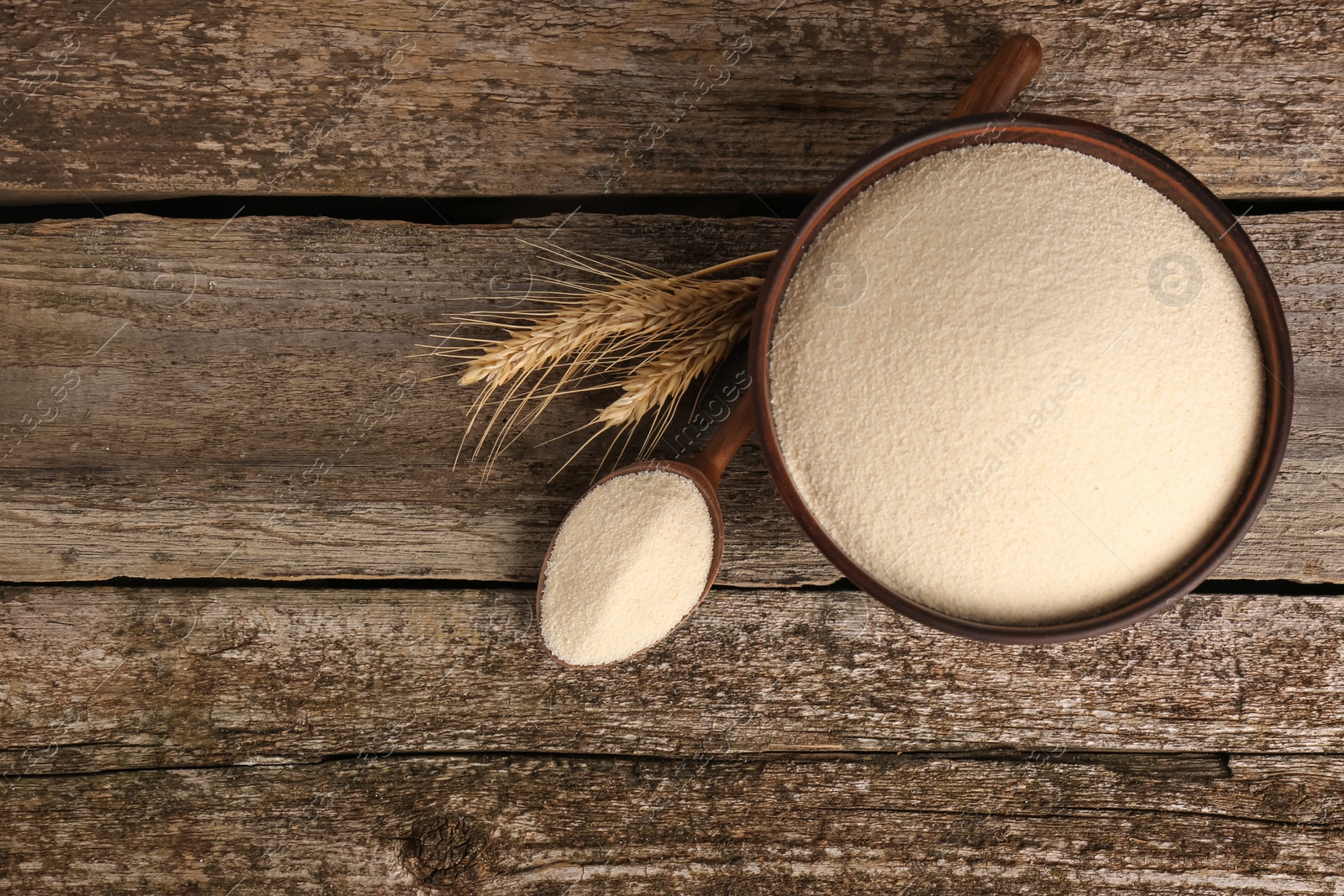 Photo of Semolina and spikelets on wooden table, flat lay. Space for text