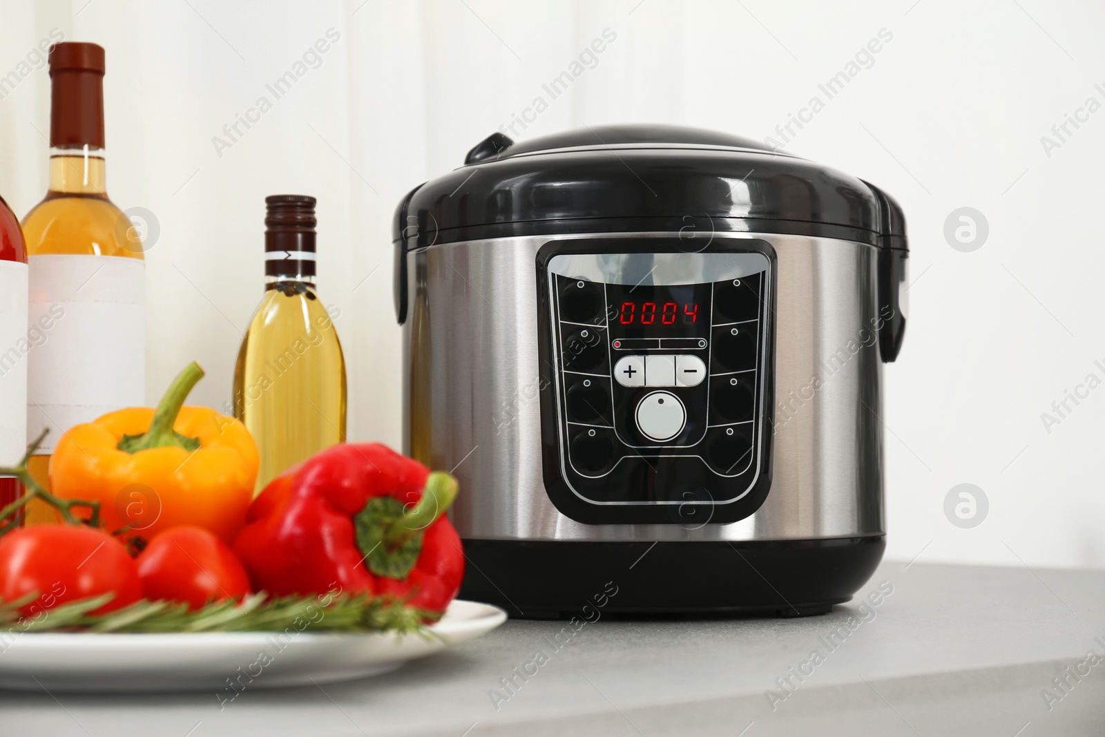 Photo of Modern multi cooker and products on table in kitchen