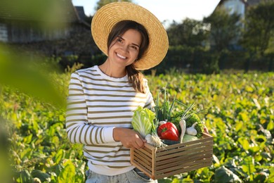 Photo of Woman with cratedifferent fresh ripe vegetables on farm
