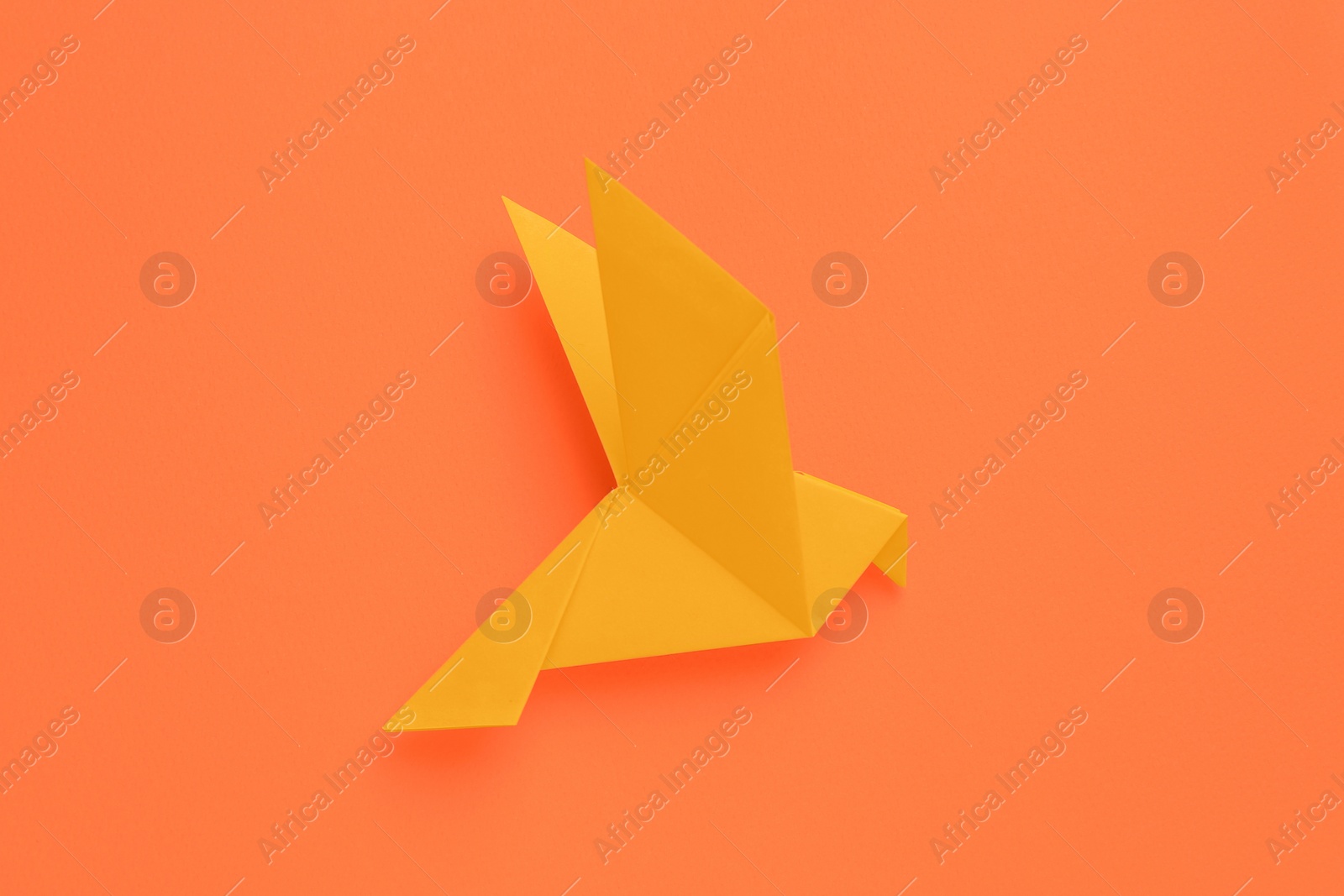 Photo of Beautiful origami bird on orange background, top view