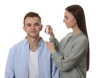 Photo of Woman spraying medication into man's ear on white background