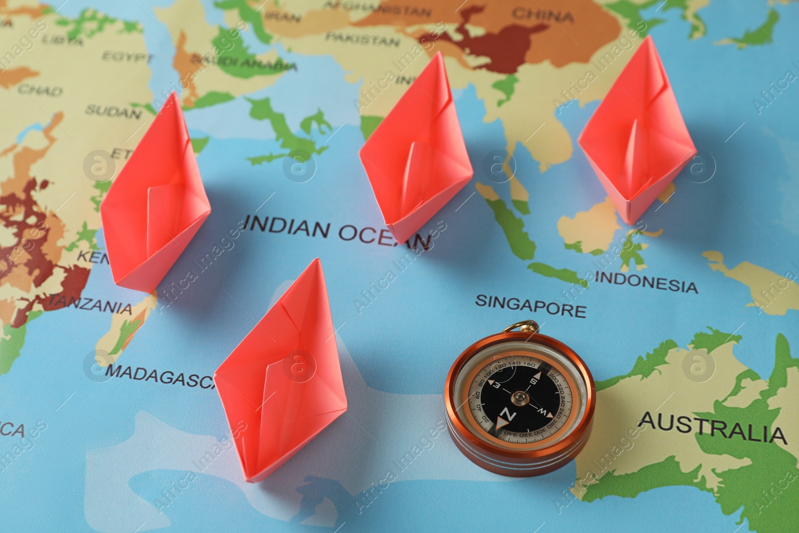Photo of Bright paper boats and compass on world map, above view