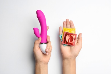 Photo of Woman with vibrator and condoms on white background, top view. Sex game