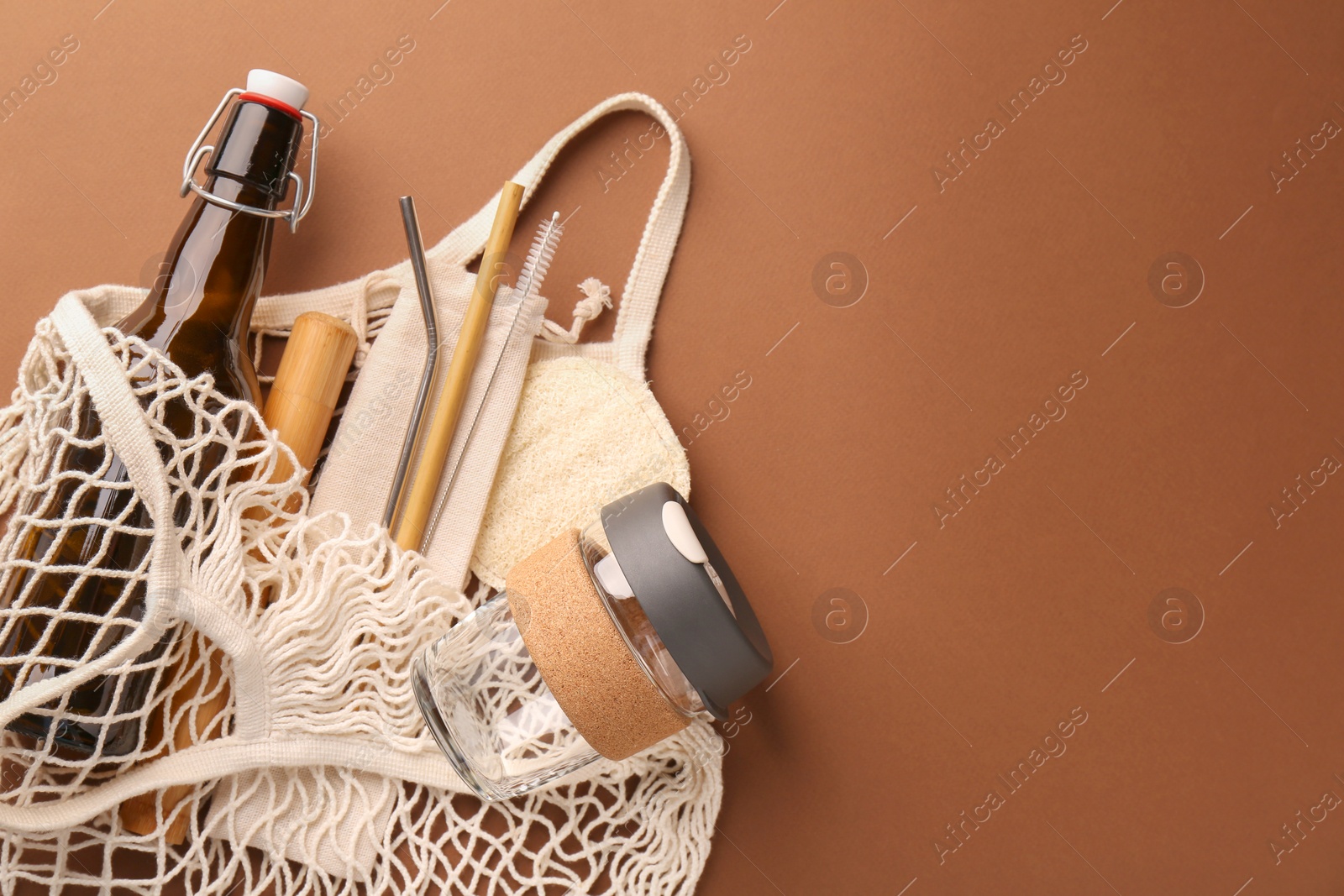 Photo of Fishnet bag with different items on brown background, top view and space for text. Conscious consumption