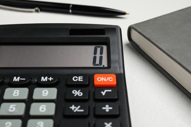 Calculator and office stationery on white table, closeup