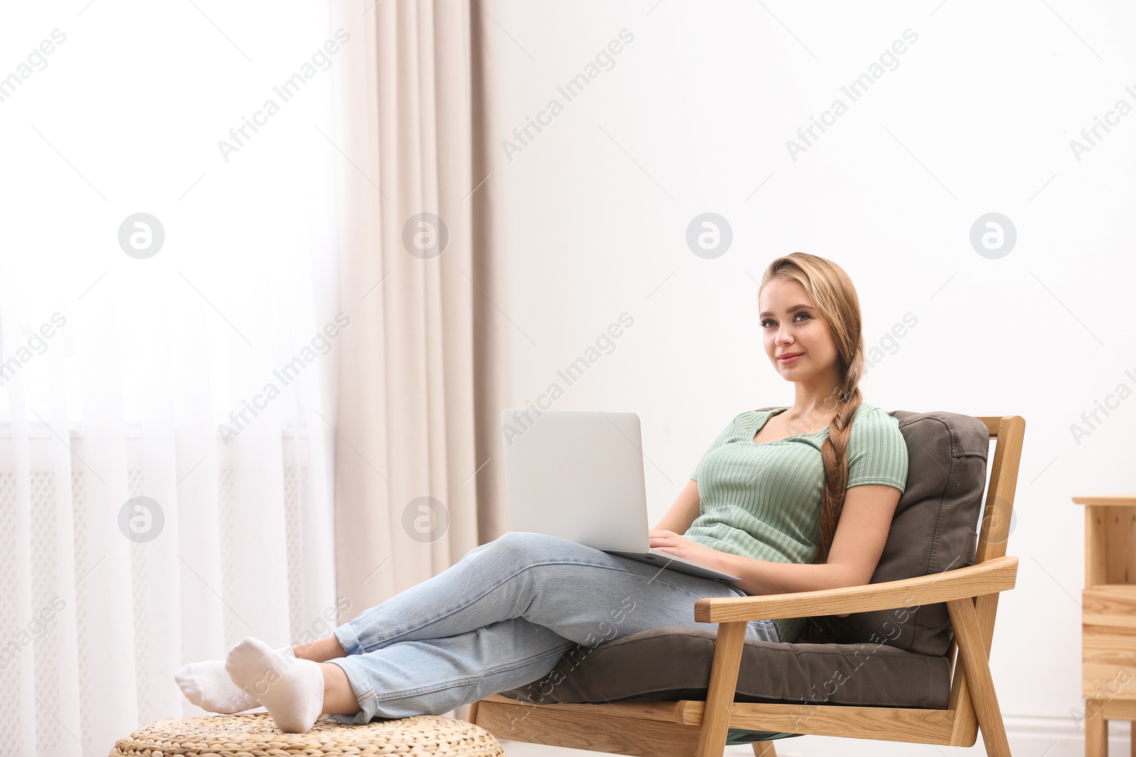 Photo of Young woman with laptop sitting in armchair at home