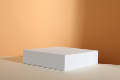 Photo of Presentation of product. Podium and shadows on orange background. Space for text